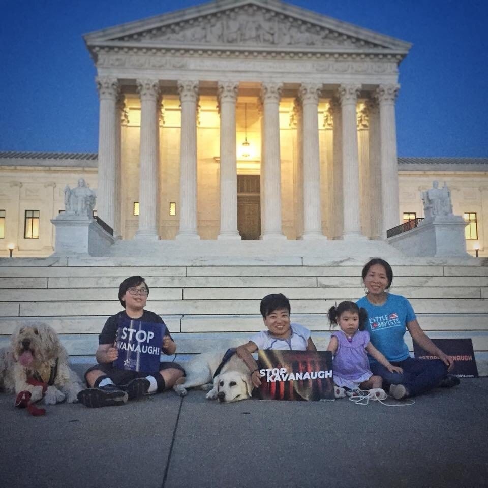 [IMAGE DESCRIPTION: photo of four Little Lobbyists families and two service dogs sitting on the ground in front of the U.S. Supreme Court steps]