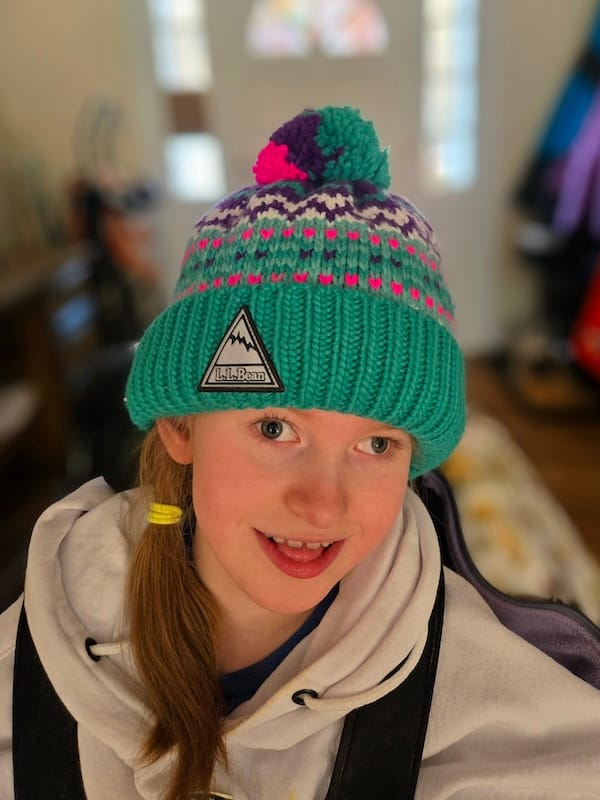 Olivia wearing a hoodie and beanie, smiling mischievously. 