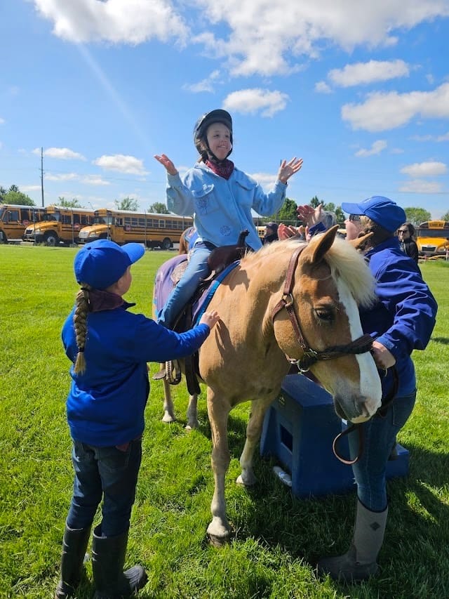 Audrey gesturing with excitement as she sits on a horse.