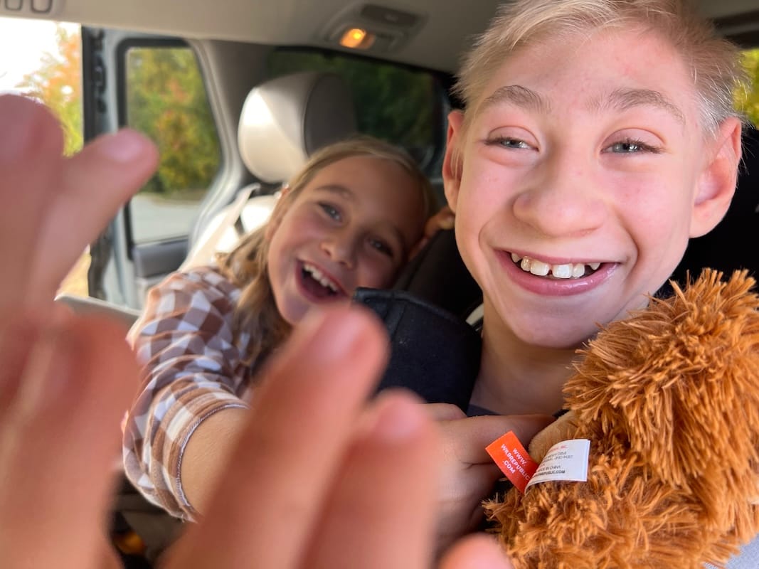 A smiling James and Rafe in a car, giddy and snuggling.
