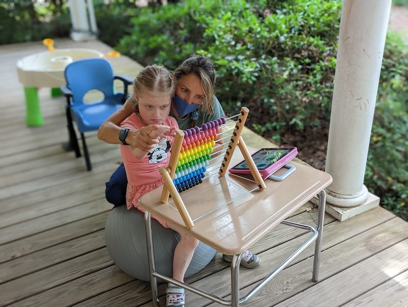 Emma and a companion working with a toy and her iPad