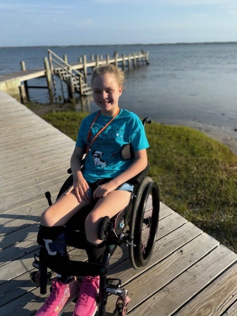 Vivi seated in her wheelchair on an accessible boardwalk