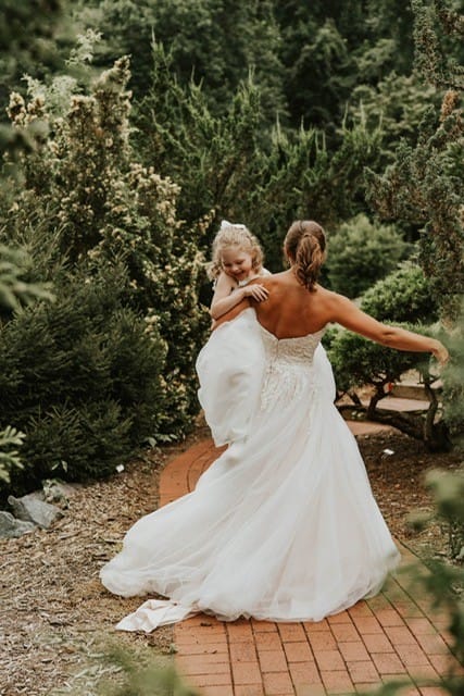 Emma smiling and laughing as a bride scoops her up in the air.