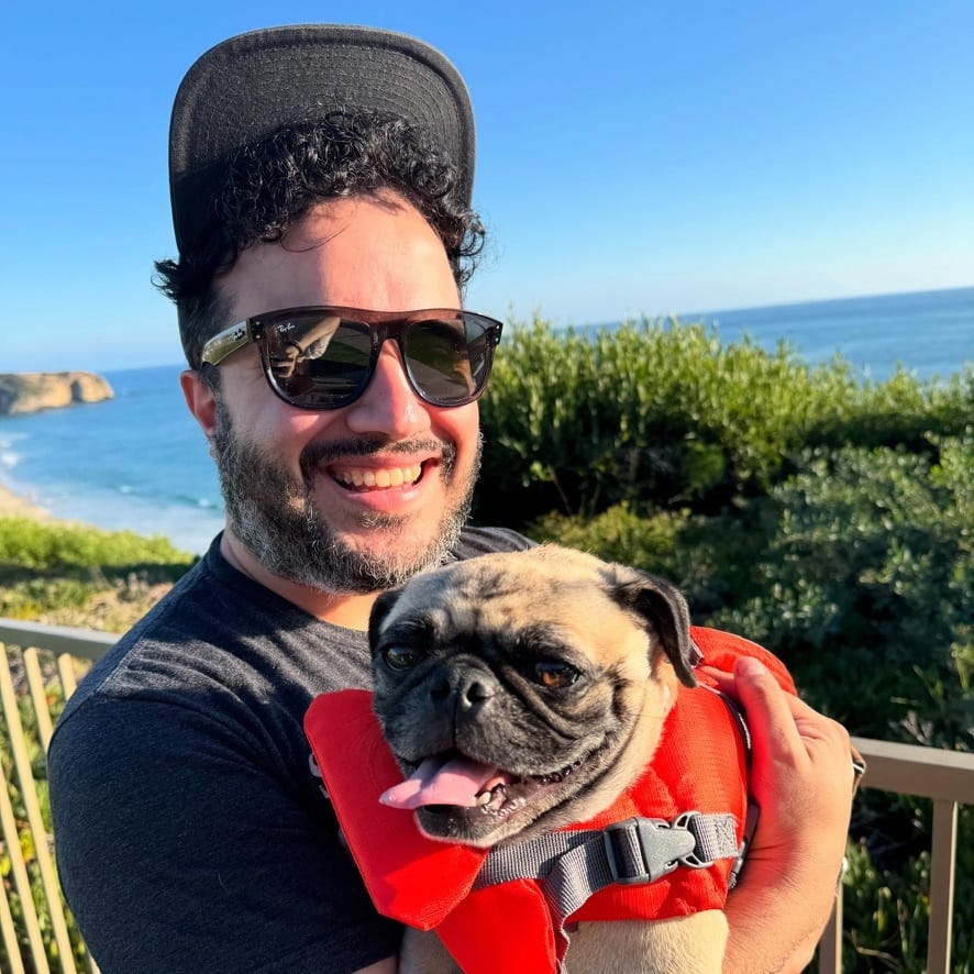 A smiling Juan Escalante holding a dog friend.