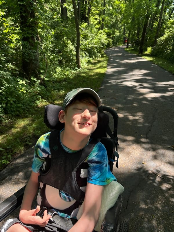 Danny Robeson using his wheelchair on a paved path in a park.