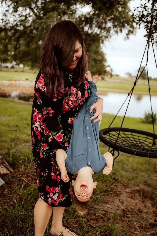 Logan laughing in Mel's arms as she swings him upside-down.