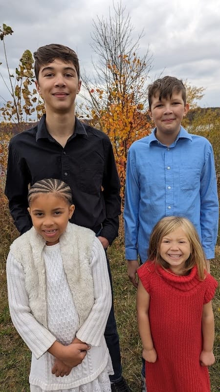 Four children beaming in a family photo.
