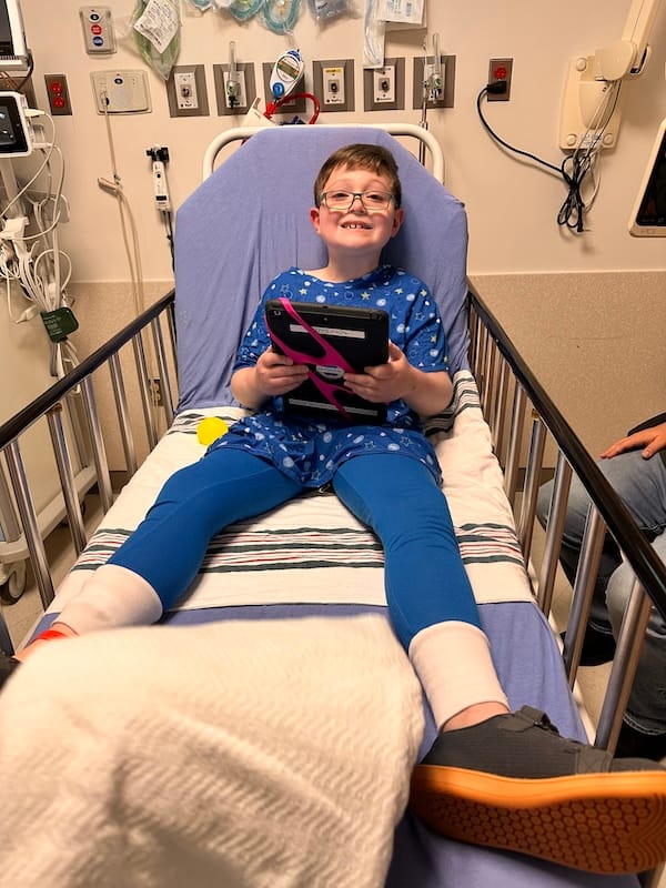 Cole grinning as he lies in a hospital bed.