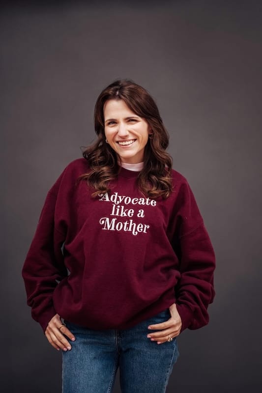 Alexis wearing an "advocate like a mother" sweatshirt and smiling for the camera.