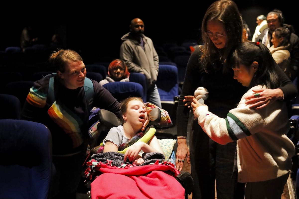 June center frame, in her wheelchair, meeting members of the cast.