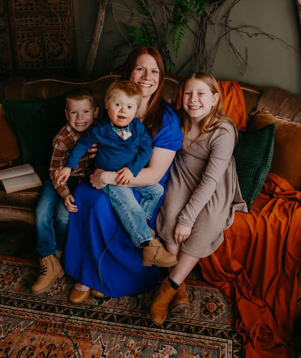 Teresa, Charla, Anthony, and Alex posing on a couch in a room with warm-toned decor and a colorful carpet.