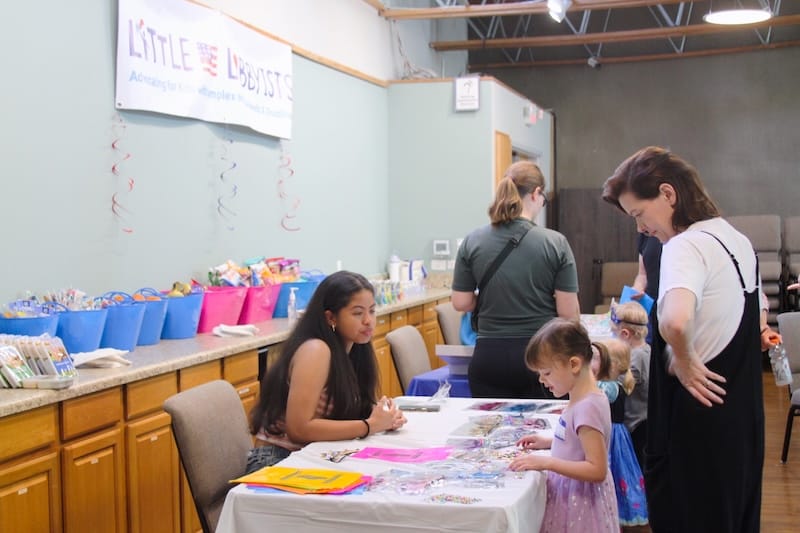 Attendees at the Drag Queen Story Hour enjoying a table of sensory and fun items.