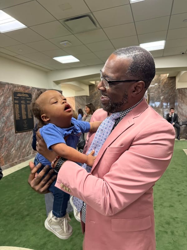 A Black man with glasses holding Landry, a Black child with Down Syndrome