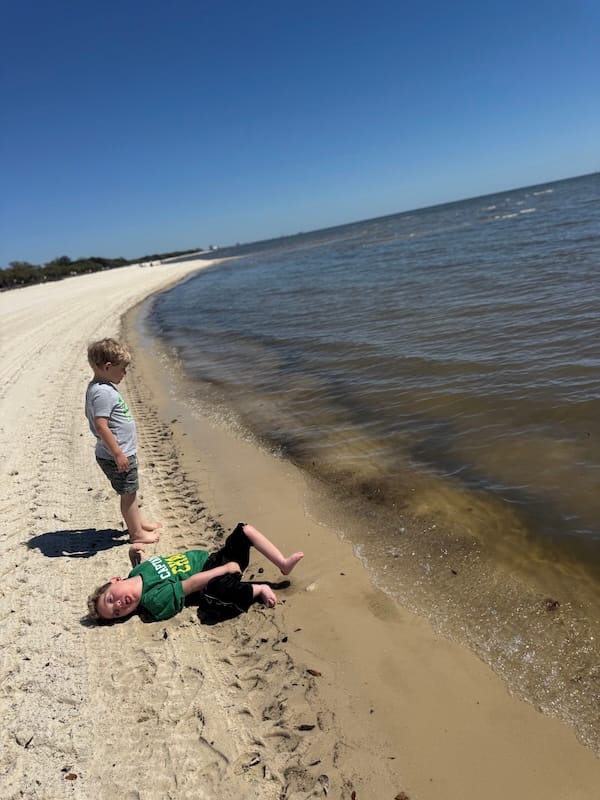 Peter and Zachary enjoying a day at the beach. Peter's feet pedal happily near the waves.