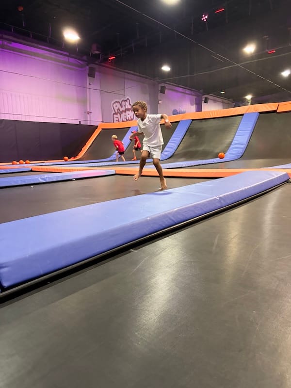 Jayden running down a gymnastics mat, limbs akimbo.