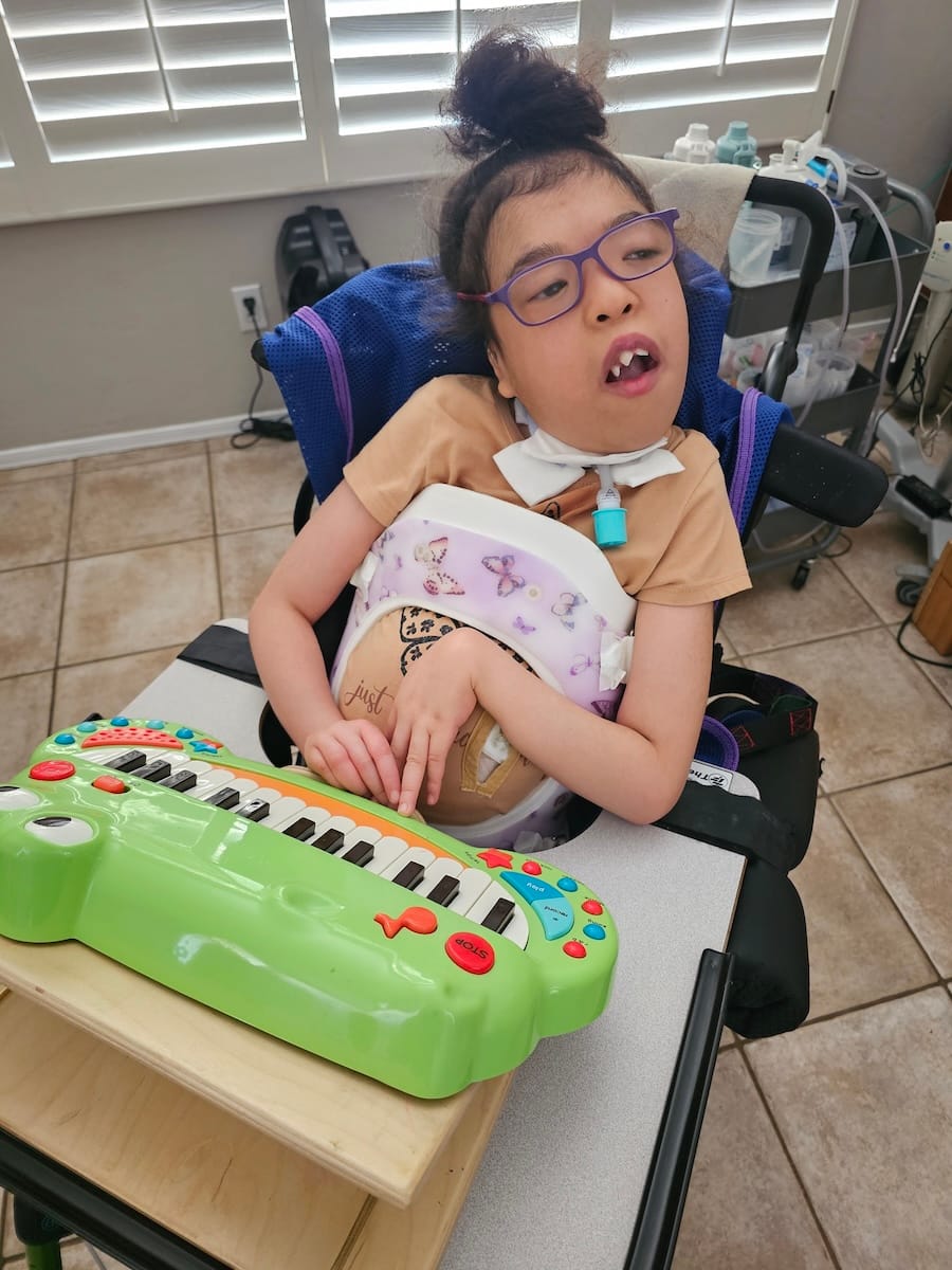 Madison in her wheelchair with a piano.