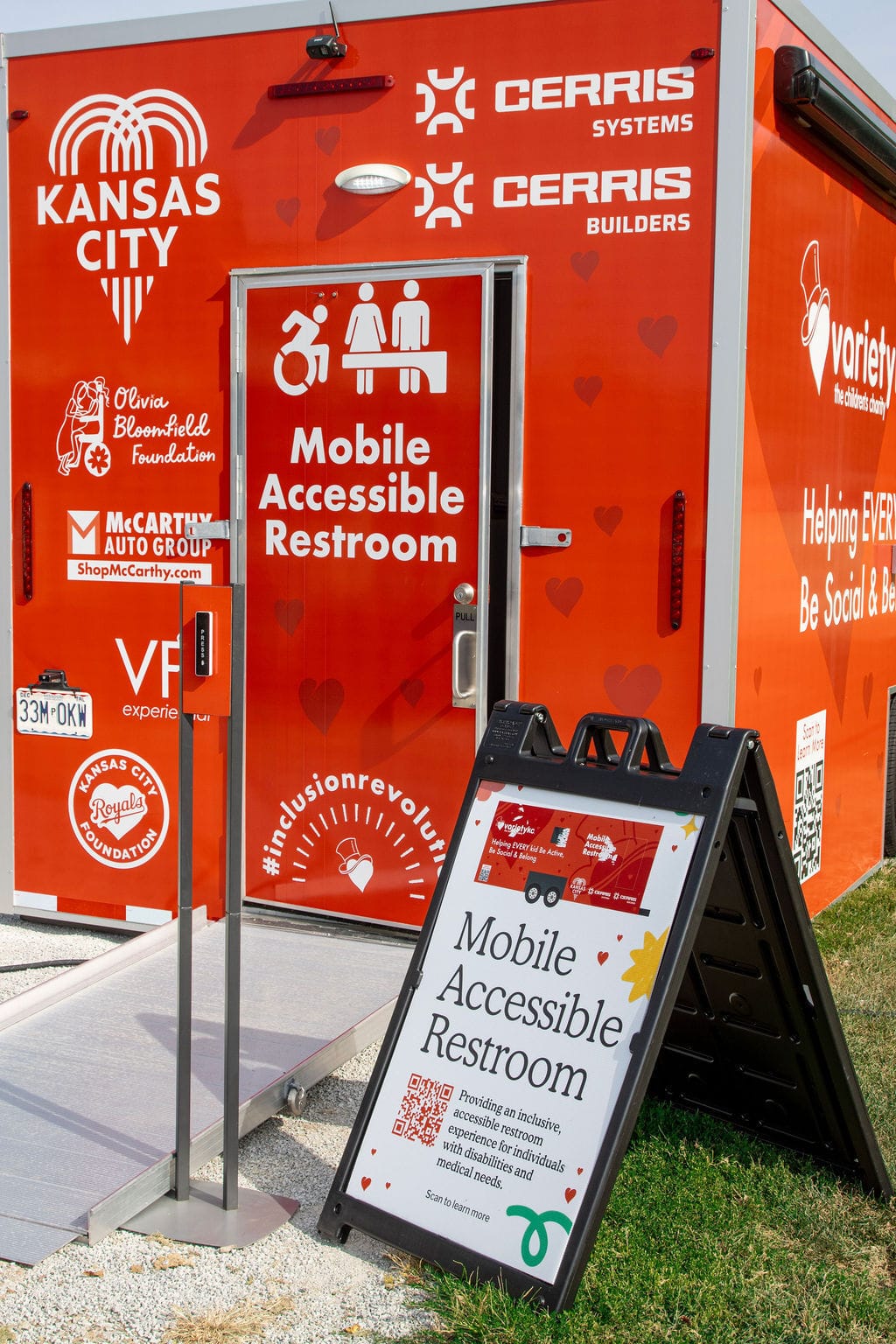 A mobile accessible restroom with ADA compliant features and a sign with more information.