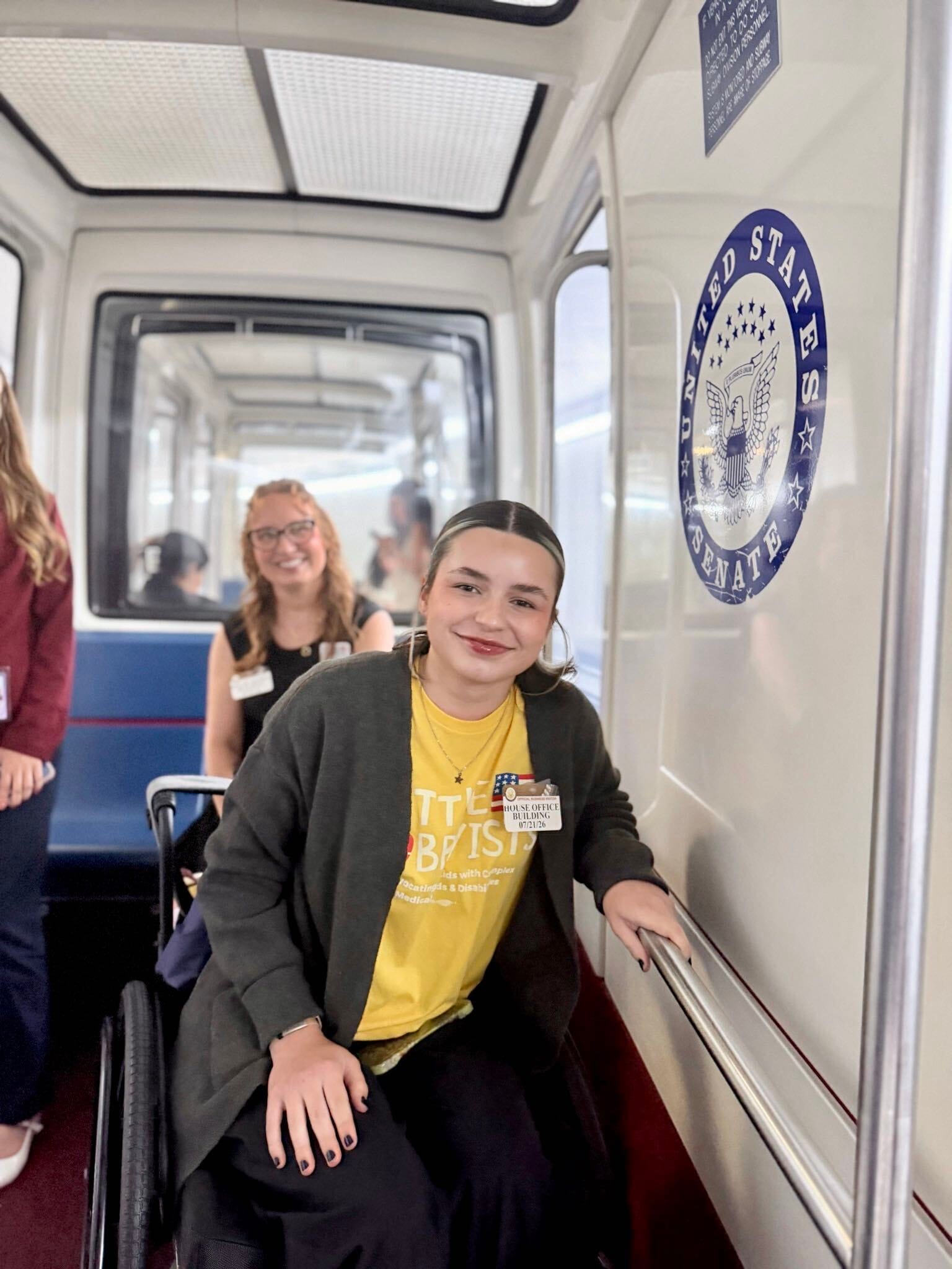 Grace, a smiling woman in a wheelchair with dark nails, rides the Senate train