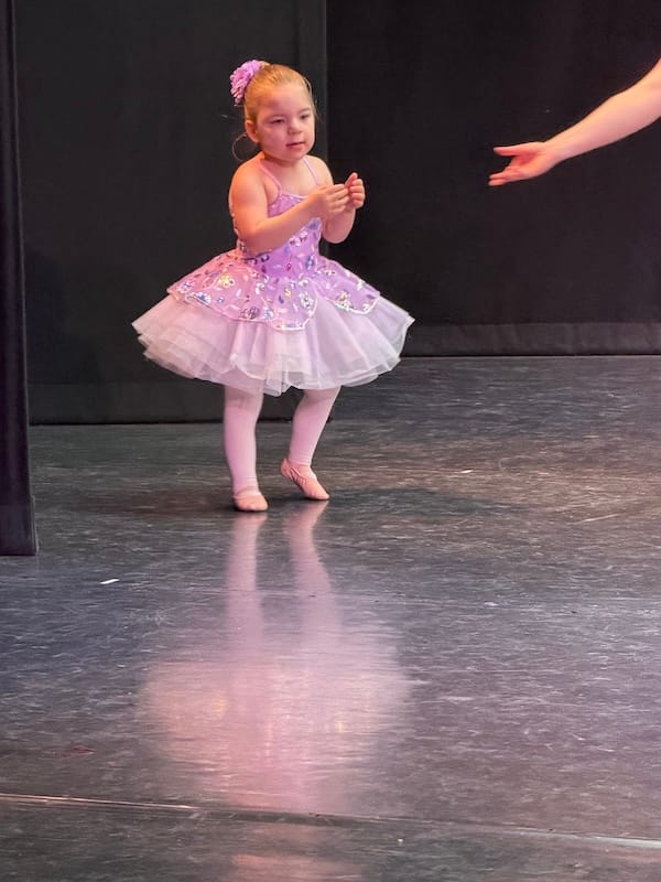 Violette in a pink ballet costume with soft flats dancing on a stage.