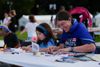 A smiling parent next to their child, making collages at a Protect Medicaid Summer event.