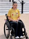 Grace, a smiling woman in a yellow Little Lobbyists tee, seated in her wheelchair at the Capitol