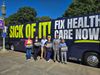 Smiling advocates in front of the Sick of It! Fix Health Care Now! Bus.