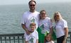 The LaVigne family in matching green and white Riley's Super Squad shirts, posing by the water.