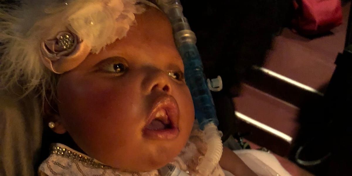 Ansley, a biracial child wearing clothes fit for a princess with a beautiful floral fascinator, at the ballet.