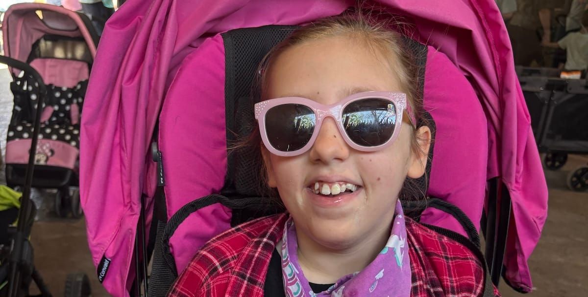 Audrey stylish in pink with big pink sunglasses and a bright smile.
