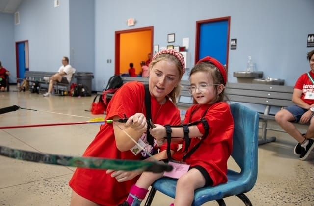 Kinsley and a friend preparing to shoot a bow and arrow.