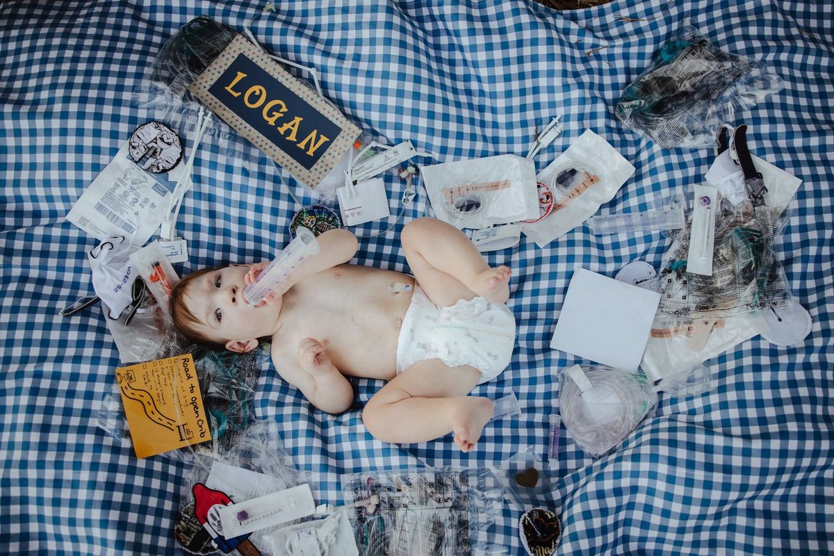 Logan as a baby lying on a blanket surrounded by medical equipment.
