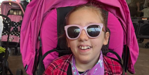 Audrey stylish in pink with big pink sunglasses and a bright smile.