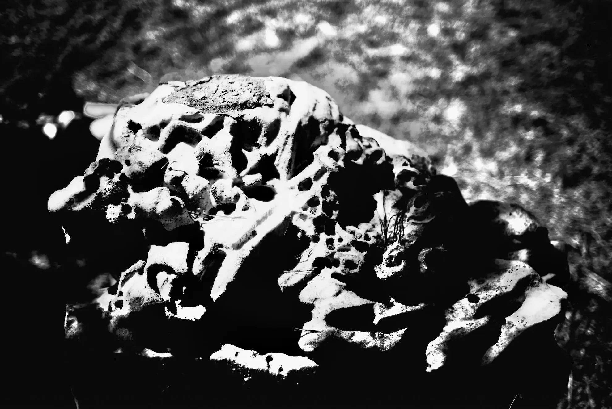 Very dark and high contrast photo of a large rock. The image is abstract and frightening.