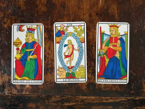 Three tarot cards, from the left: Queen of Cups, The World, Queen of Swords.