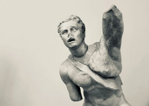 Black and white photo of an ancient statue reaching towards the viewer with a partial arm. The feeling is of mysterious yearning.