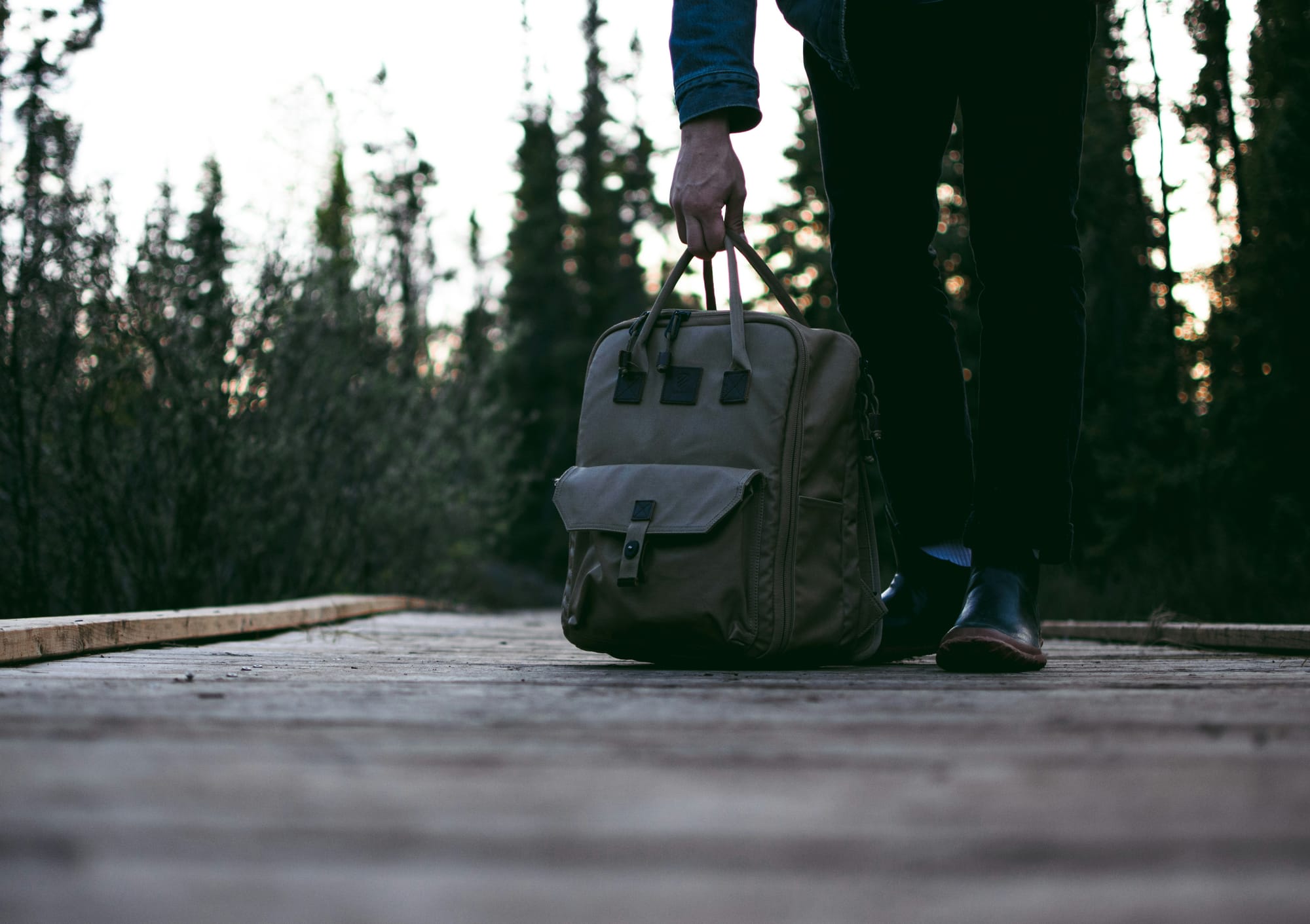 Grüner Rucksack auf Holzboden, im Hintergrund Wald