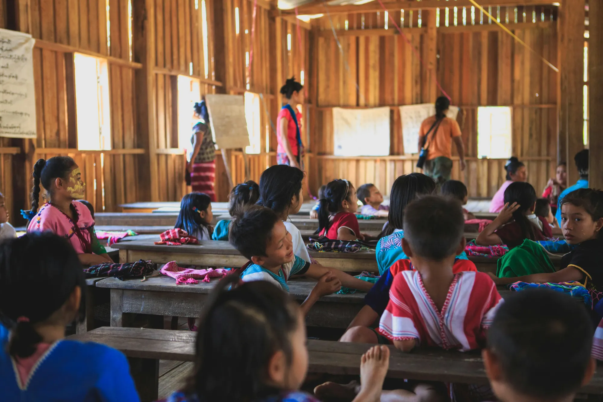 Classroom made of wood with children and teachers.