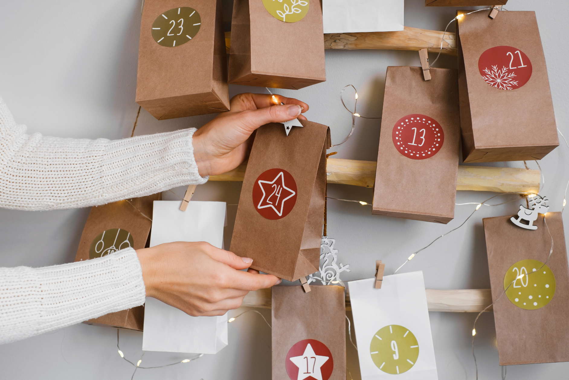 Frau hängt Säckchen mit Nummer 24 an Adventskalender