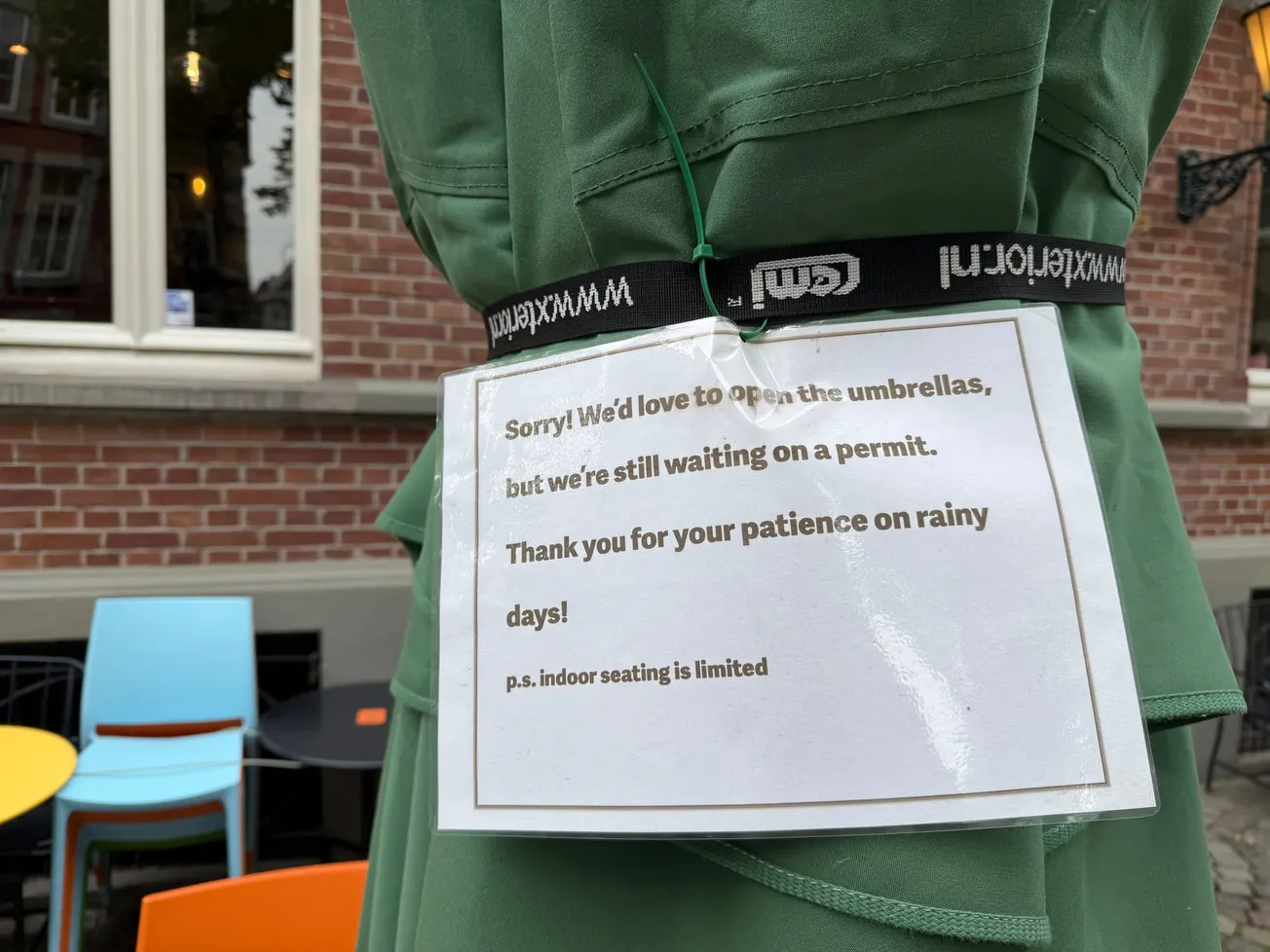Griek mag parasols al 1,5 jaar niet openen, terras in de regen