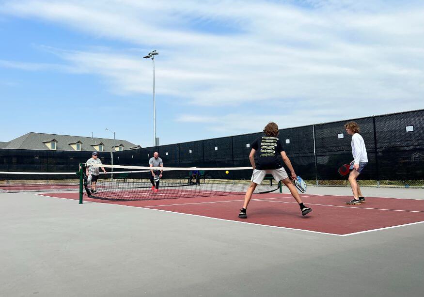 Four pickleball players playing with paddles and balls