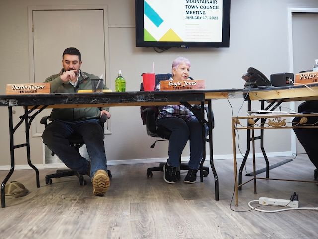 Town Council Member and Mayor Pro Tem Gayle Jones discusses changes to Mountainair's Procurement Policy. To her left is town council member Dustin Kayser. Behind her is a television which displays "MOUNTAINAIR TOWN COUNCIL MEETING JANUARY 17, 2023." 