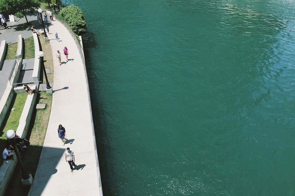 color street photography of people walking on pavement along Chicago river on a sunny day