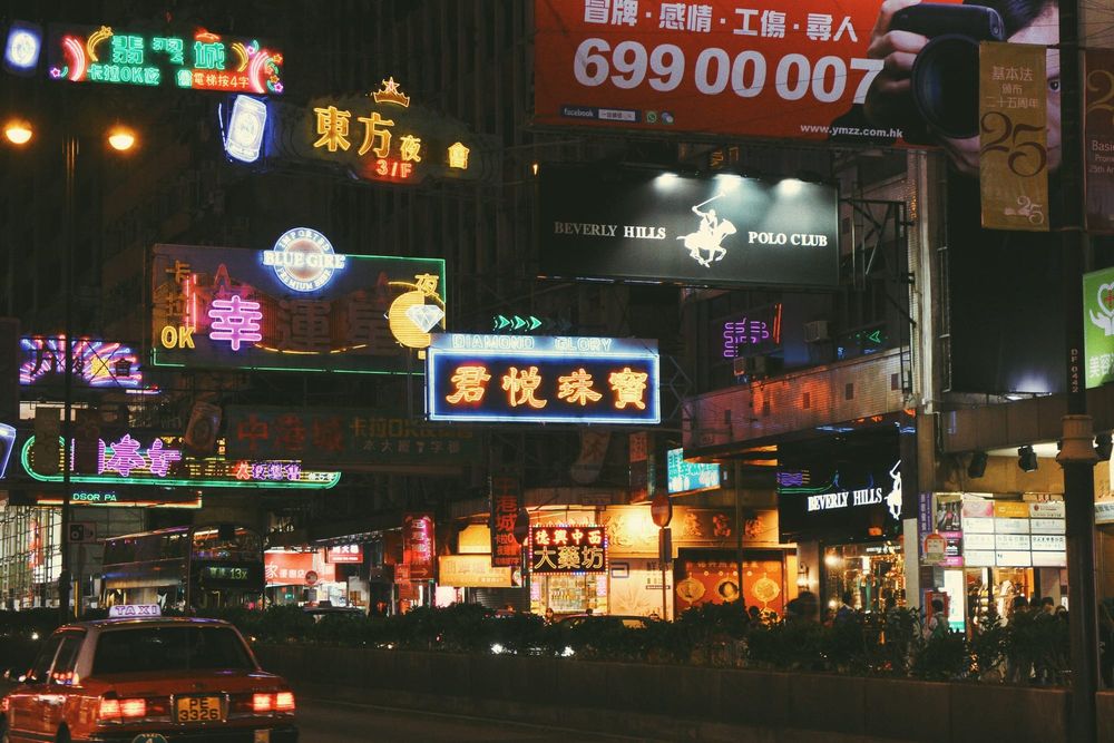color street photography of glowing neon shop signs above a busy road at night in Hong Kong, 2015