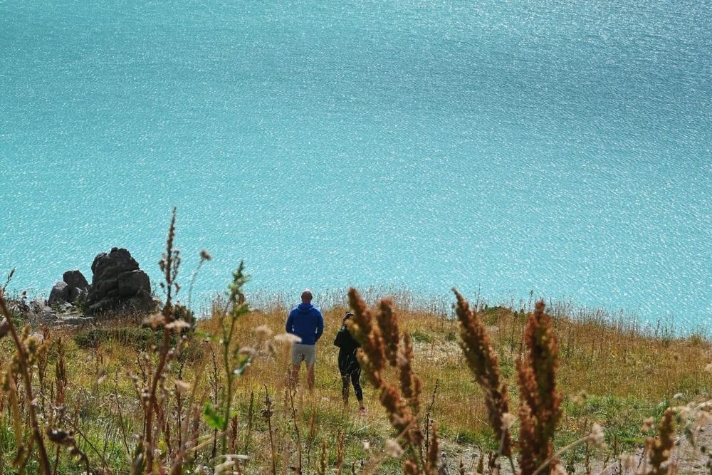 color travel photography of two people viewing Big Almaty Lake on a sunny day