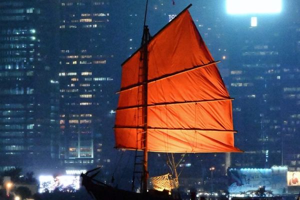 color street photography of red junk boat sailing in Victoria Harbour of Hong Kong at night