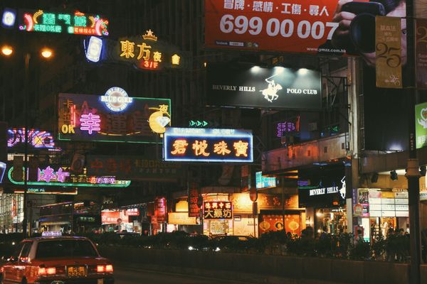 color street photography of glowing neon shop signs above a busy road at night in Hong Kong, 2015