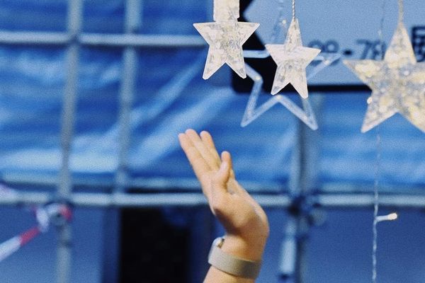 color street photography of hand reaching for star-shaped decorative lights