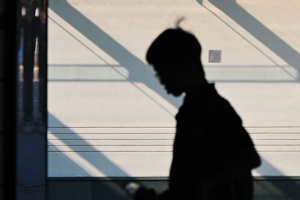 color street photography of a silhouette of a person in front of a building with lights and shadows on it 