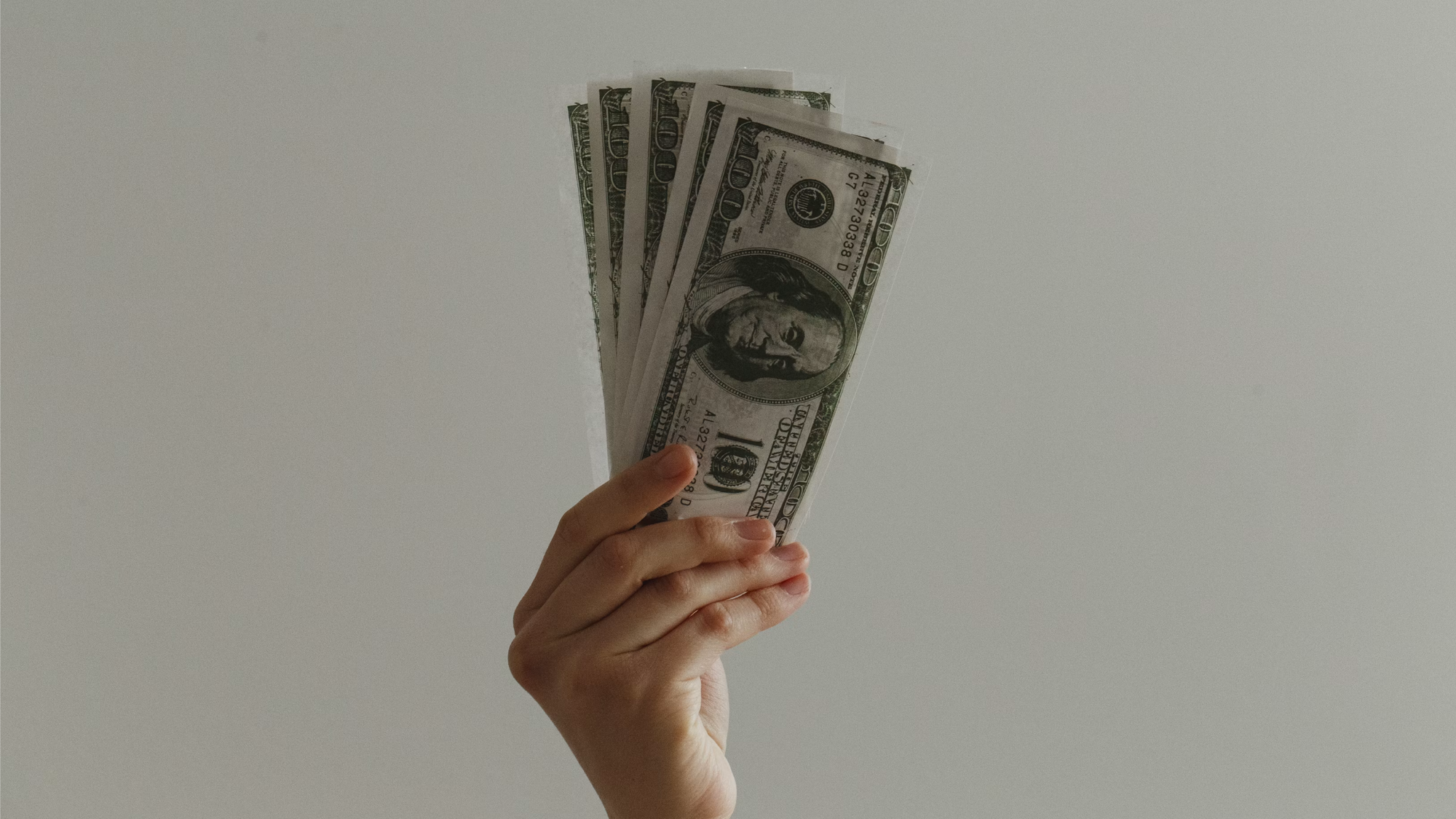 A hand hold several $100 bills