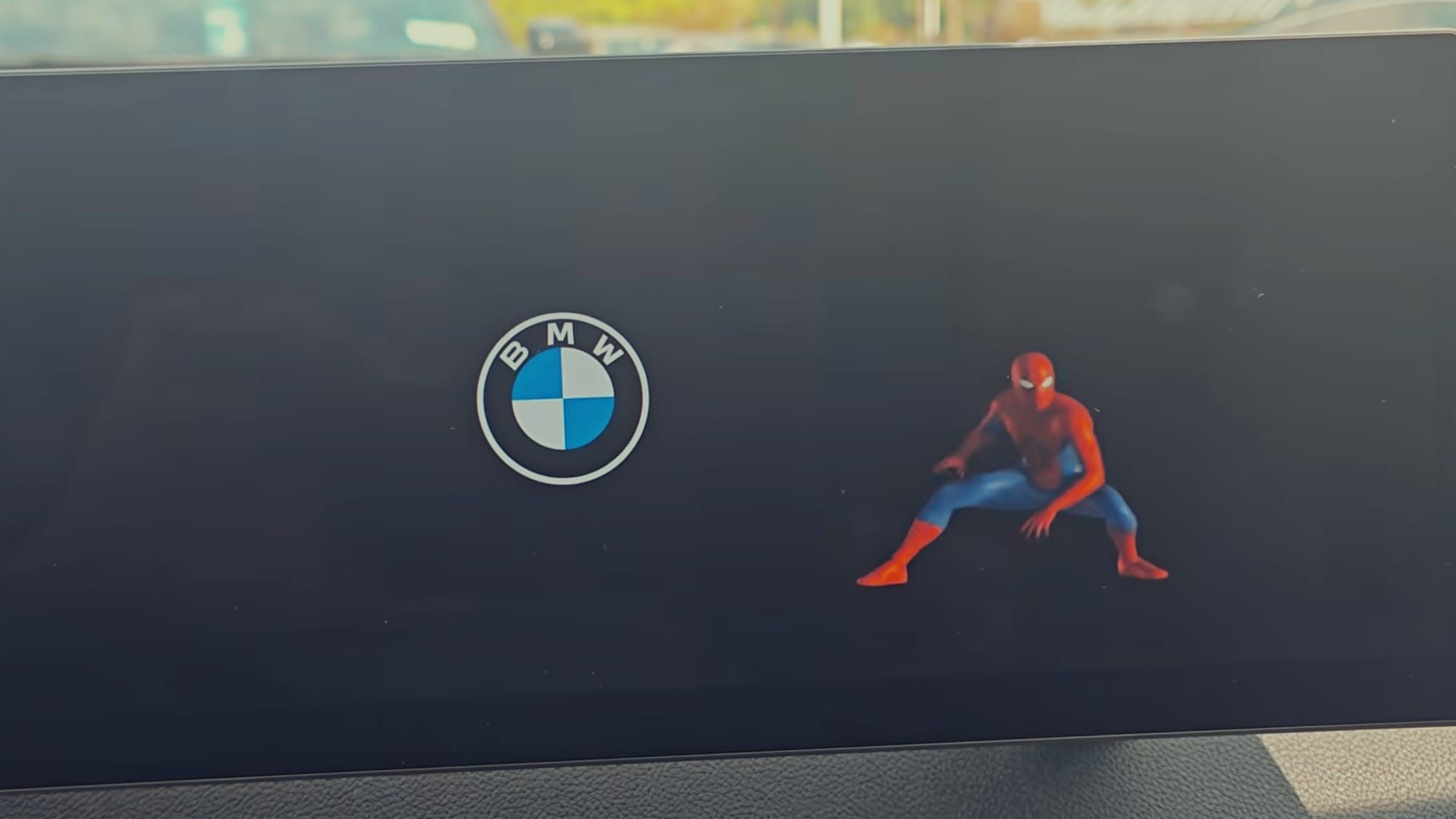 The BMW logo next to Spider-Man on the center console screen of a BMW vehicle.